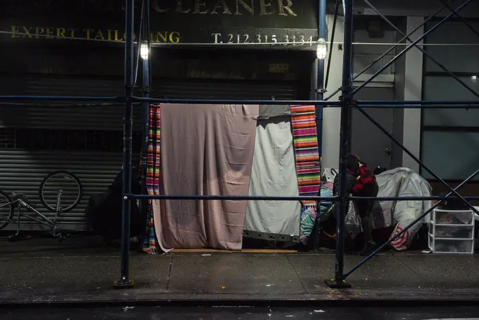 Blankets are hung on scaffolding in a homeless encampment in midtown